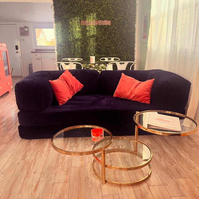 Aubergine corduroy sofa with coral cushions and round brass side tables, photographed by the buyer