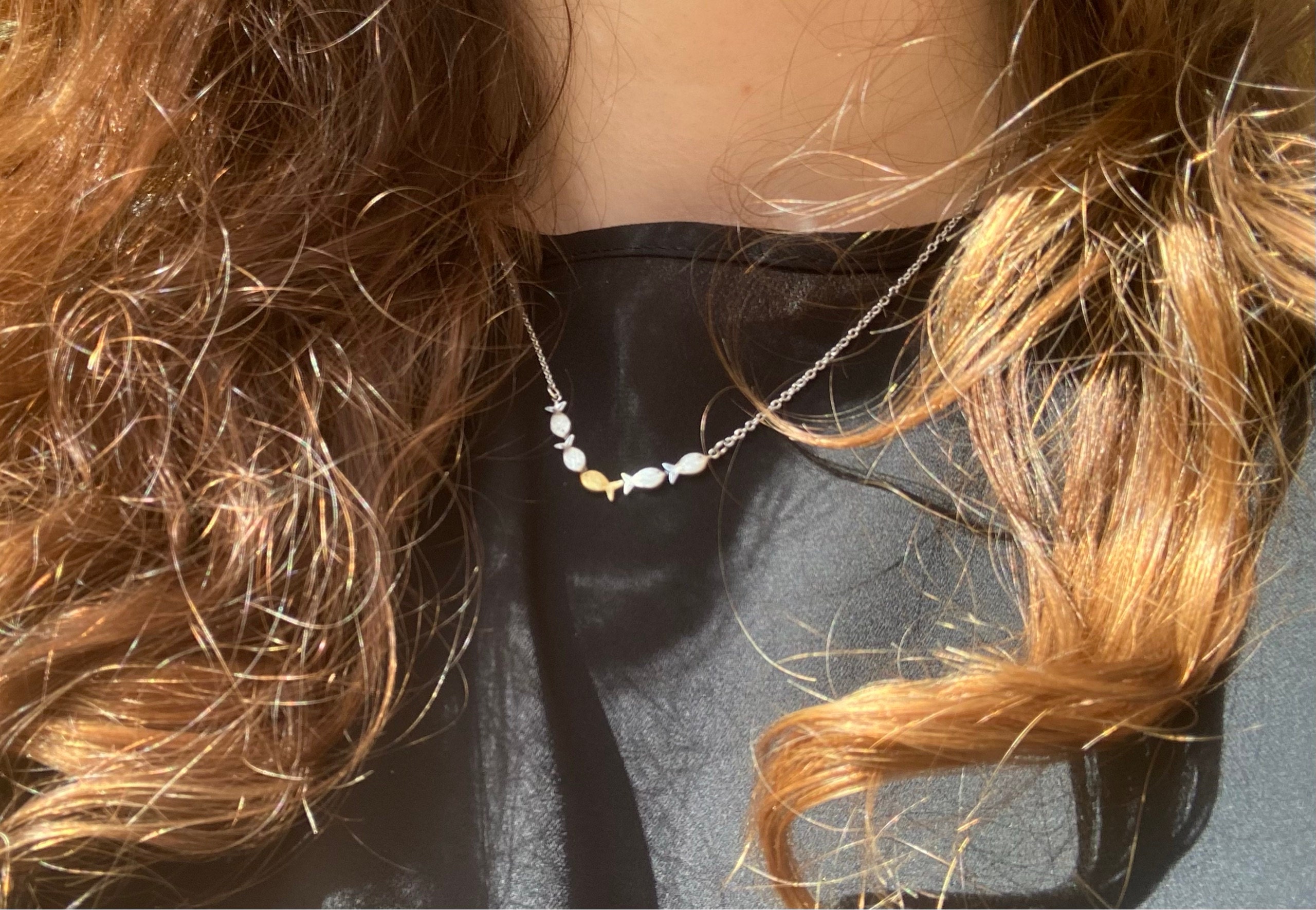 Swimming against the current. Dainty silver necklace. School of fish with one golden enameled fish swimming upstream. Gift for her.
