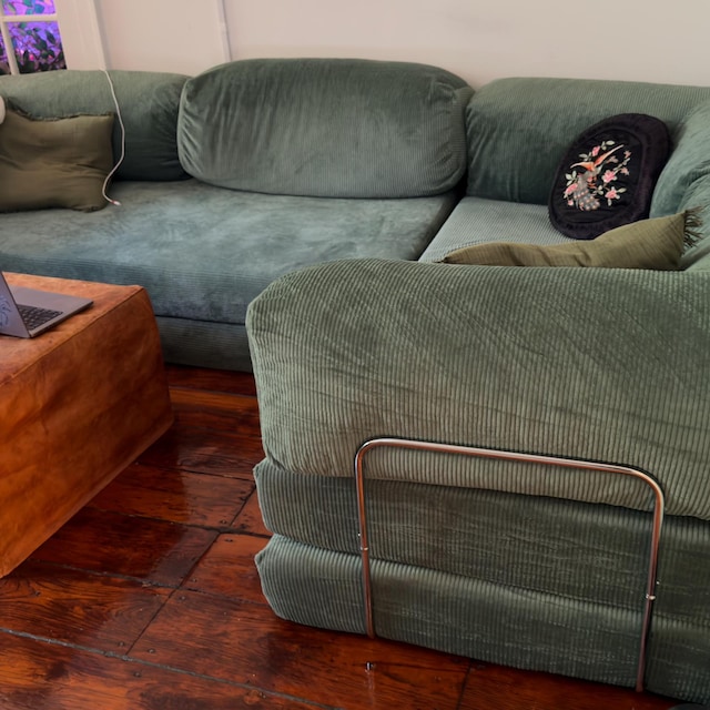 Green velvet corner sectional in a wood-panelled living room, photographed by the buyer