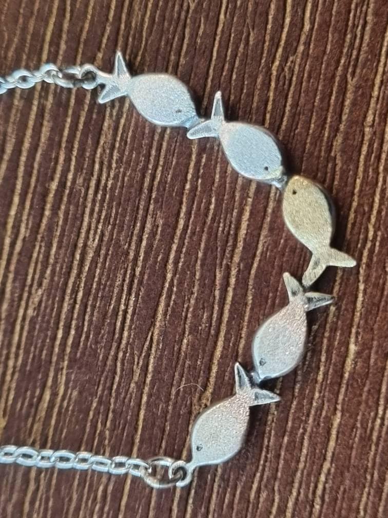 Swimming against the current. Dainty silver necklace. School of fish with one golden enameled fish swimming upstream. Gift for her.
