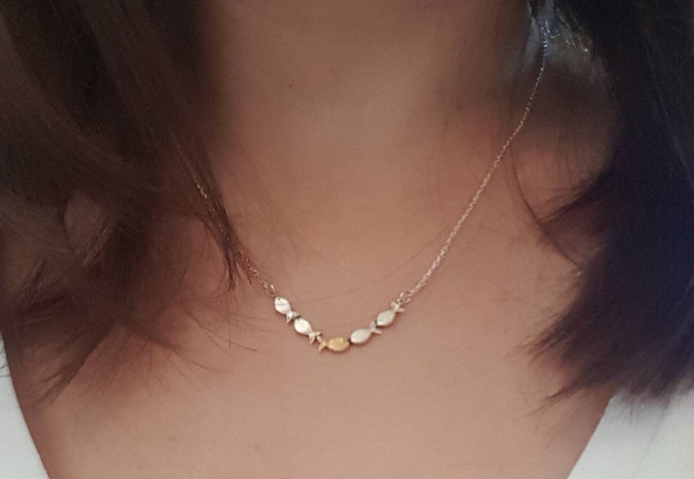 Swimming against the current. Dainty silver necklace. School of fish with one golden enameled fish swimming upstream. Gift for her.
