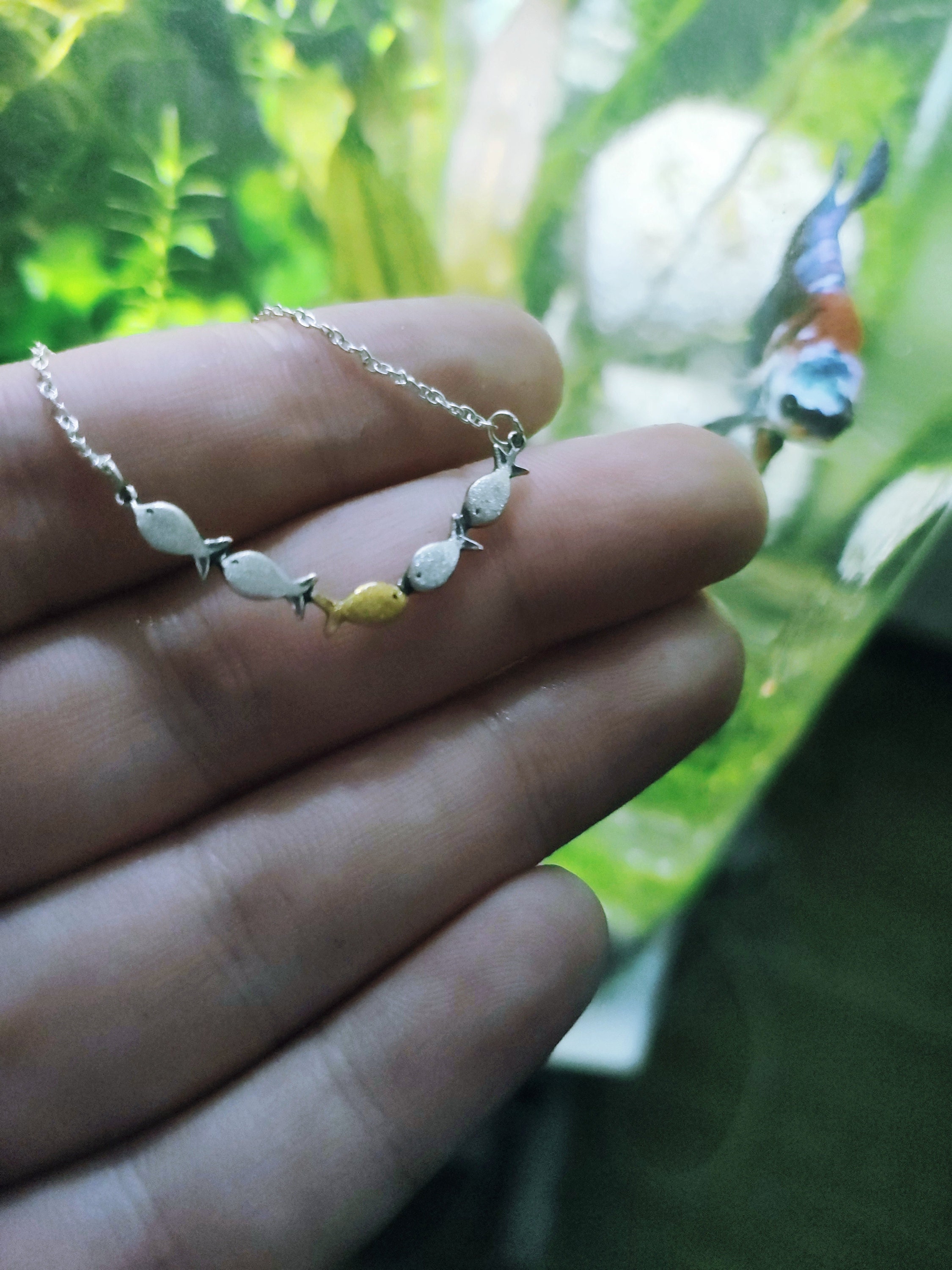 Swimming against the current. Dainty silver necklace. School of fish with one golden enameled fish swimming upstream. Gift for her.