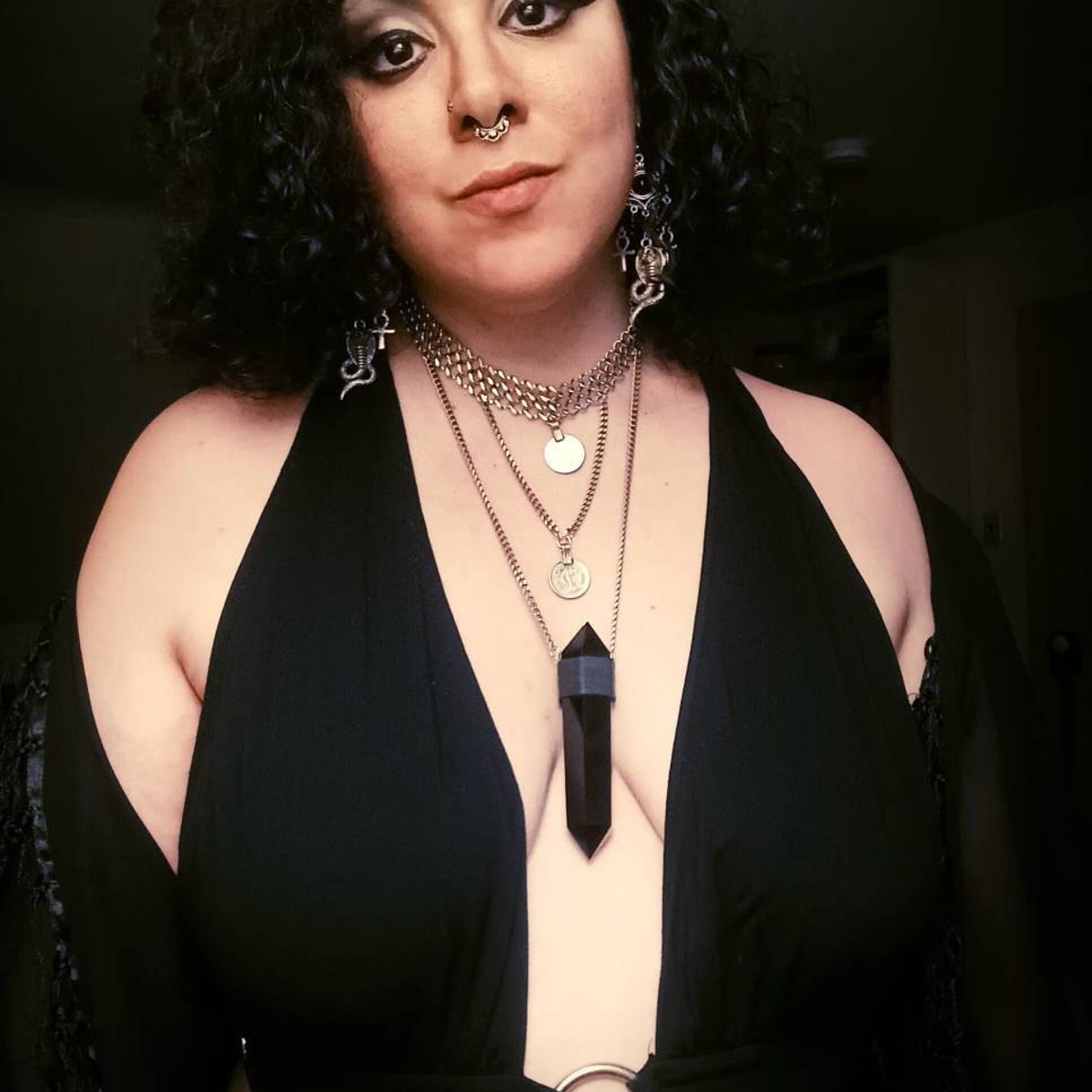 Black obsidian pendant and layered coin necklaces worn with deep v-neck black outfit and goth makeup.