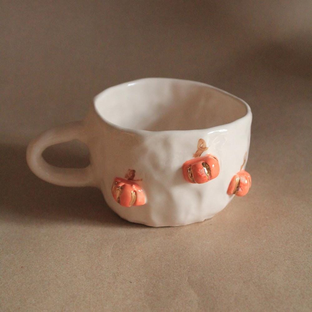 ceramic white mug with orange pumpkins on it
