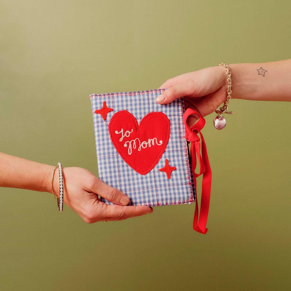 Blauw en wit gingham fotoalbum met rood hart op de voorkant waarop 