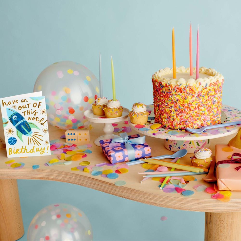 Colección de artículos de cumpleaños, como una tarjeta, una tarta, velas y globos con confeti