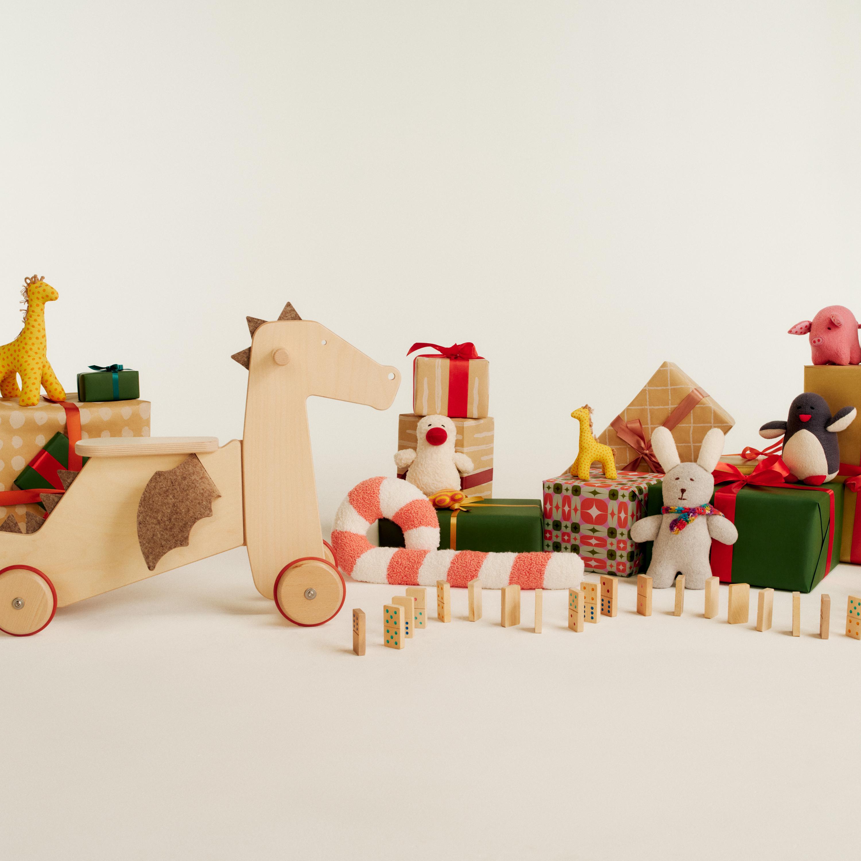 Collection of toys including ride on dragon, stuffed animals, dominos, and wrapped gifts