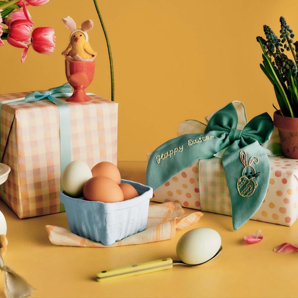 Paasgerelateerde decoraties met eieren, een paashaarstrik en een aardewerken kuiken met konijnenoren erop