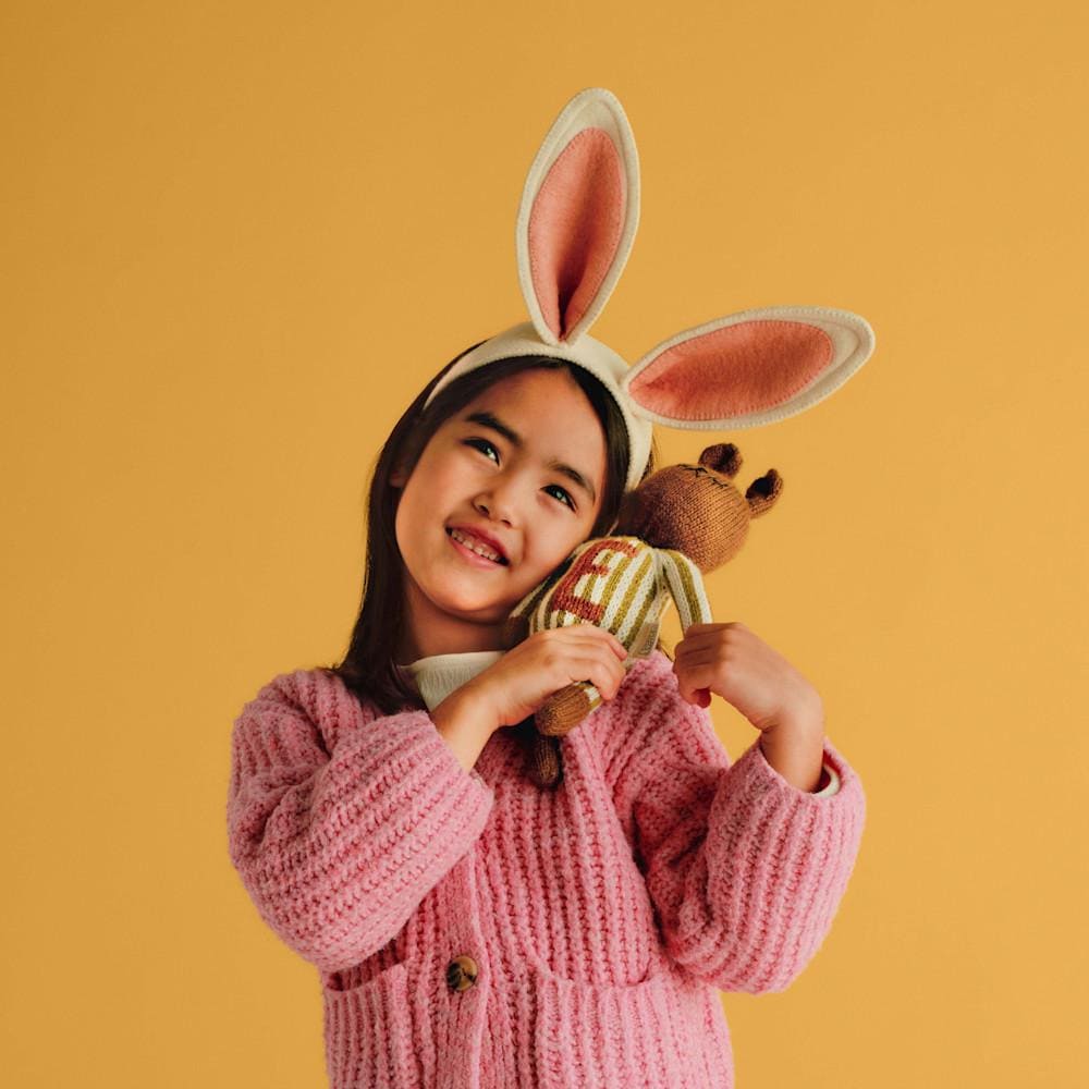 Little girl wearing bunny ears holding a bear stuffed animal with a monogrammed sweater