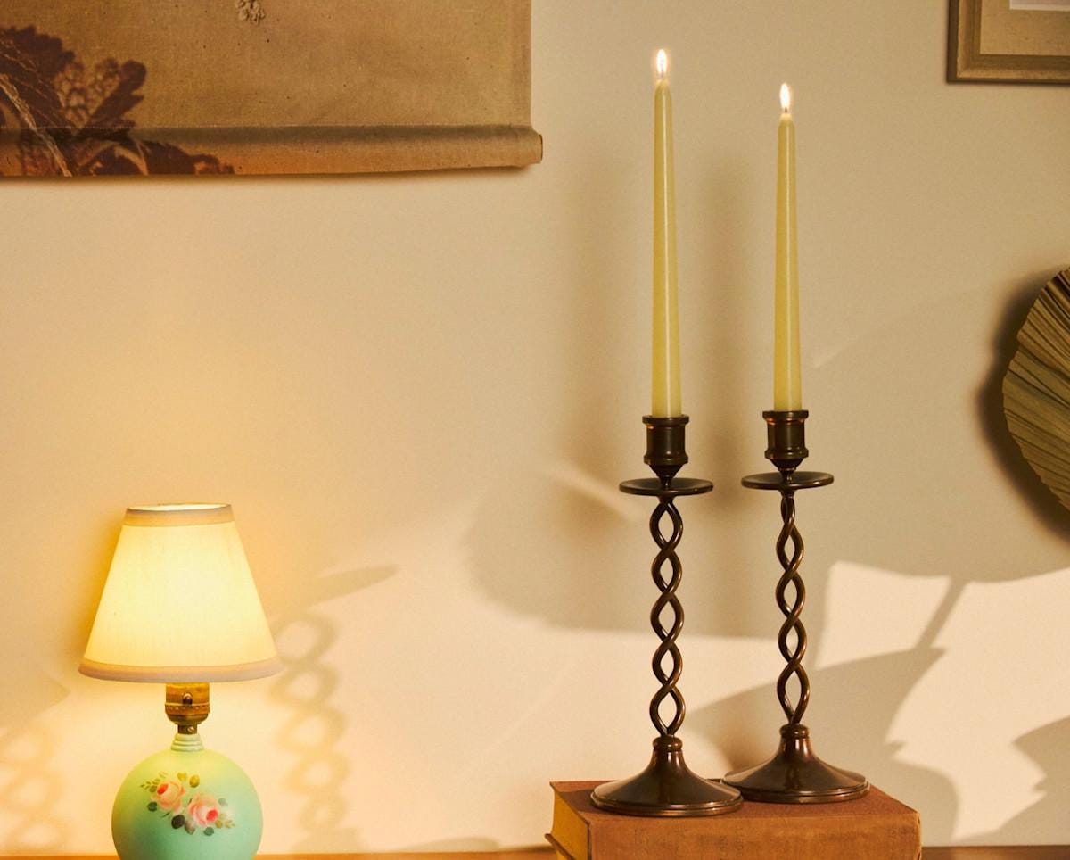 A set of black vintage candlesticks sit on top of of books.