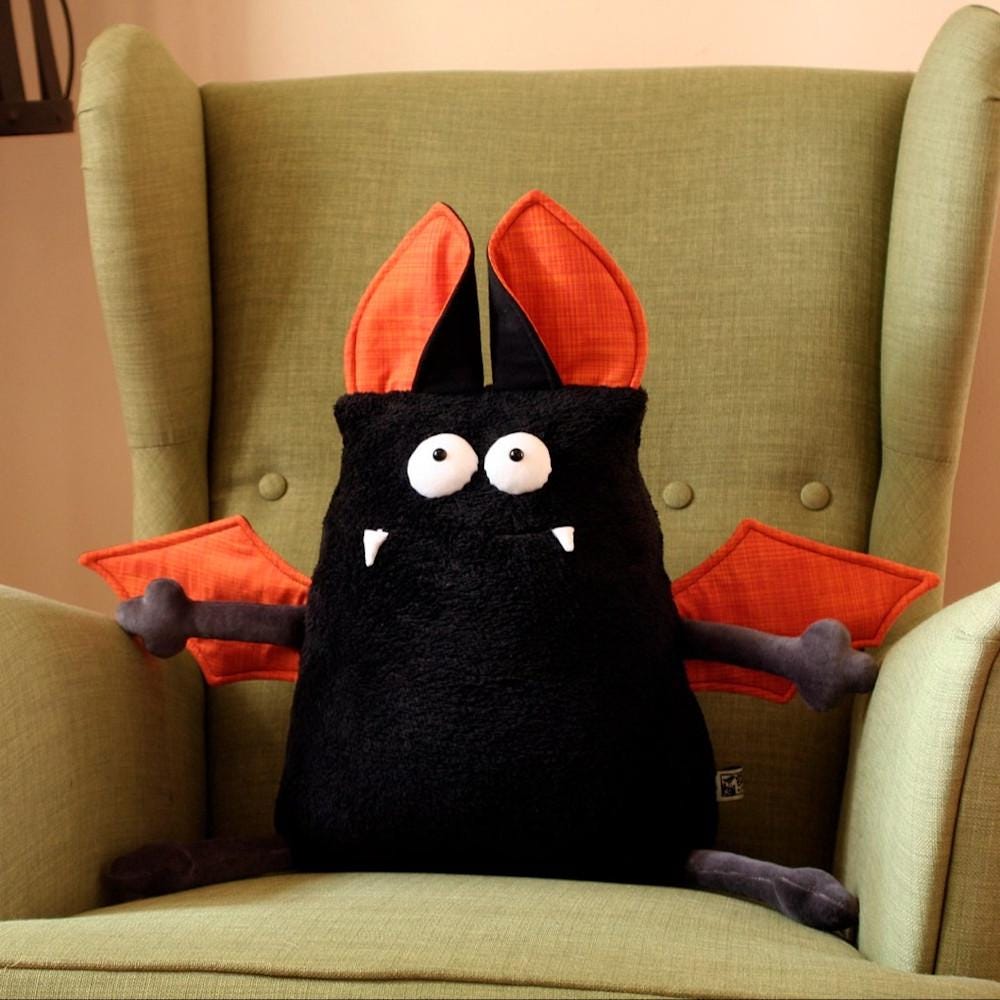 Black vampire bat cushion with orange wings and ears