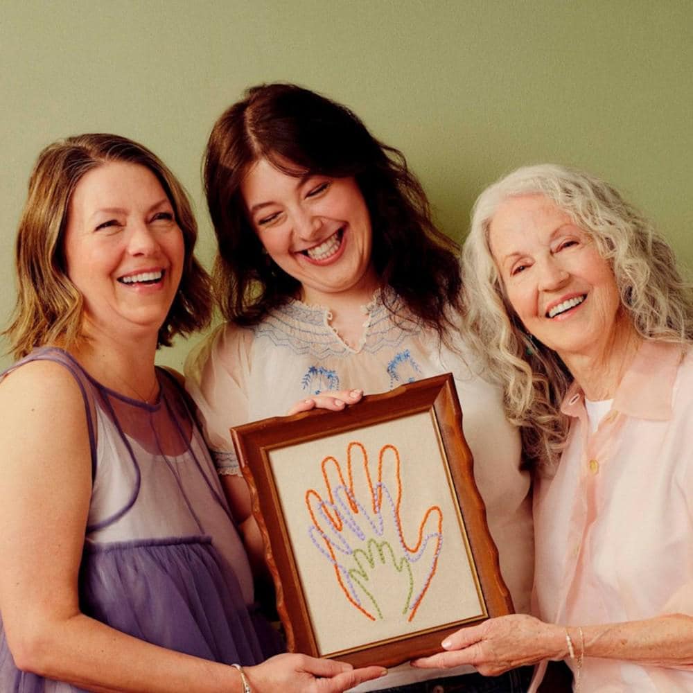 Tres generaciones de mujeres sosteniendo una lámina de una mano