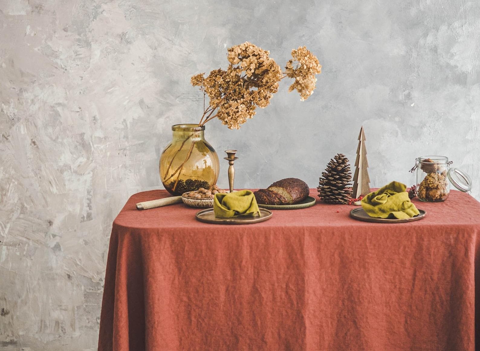 A table is set with a rust orange table cloth and fall decor settings.