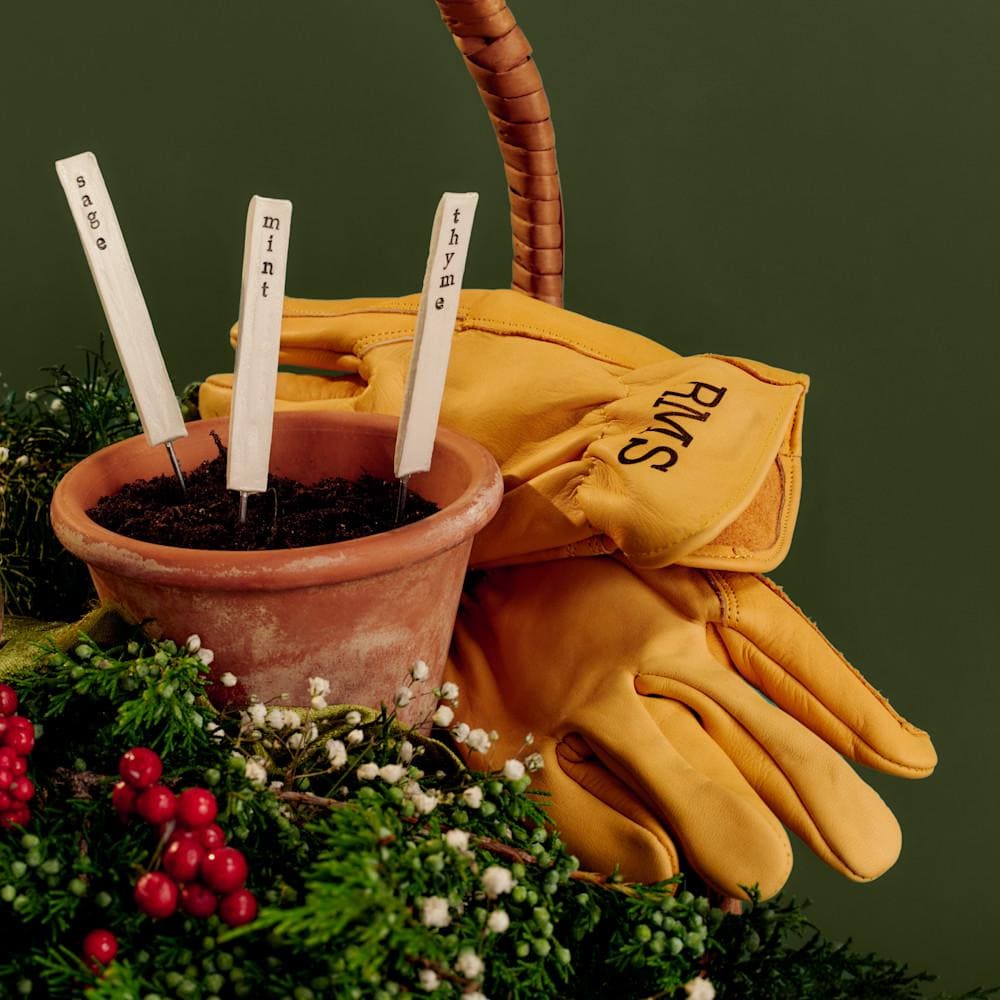 Monogrammed gardening gloves and a terracotta pot with ceramic herb markers