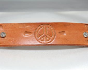 Leather barette stamped with a peace sign.