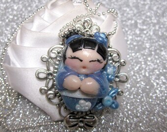 sautoir ketting kleine blauwe skokeshi en haar ketting heeft ballen