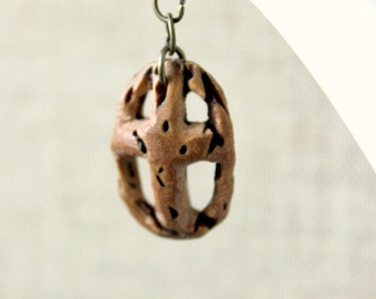 cross necklace whittled by hand out of a peach seed