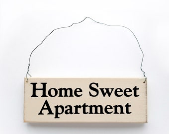 Wood Sign Saying 'Home Sweet Apartment' White Wood Sign With Black Lettering.