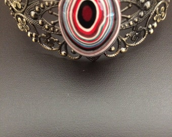 Ornamental cuff bracelet with fordite cabachon centerpiece