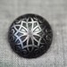 Dark grey metal button with geometric motif