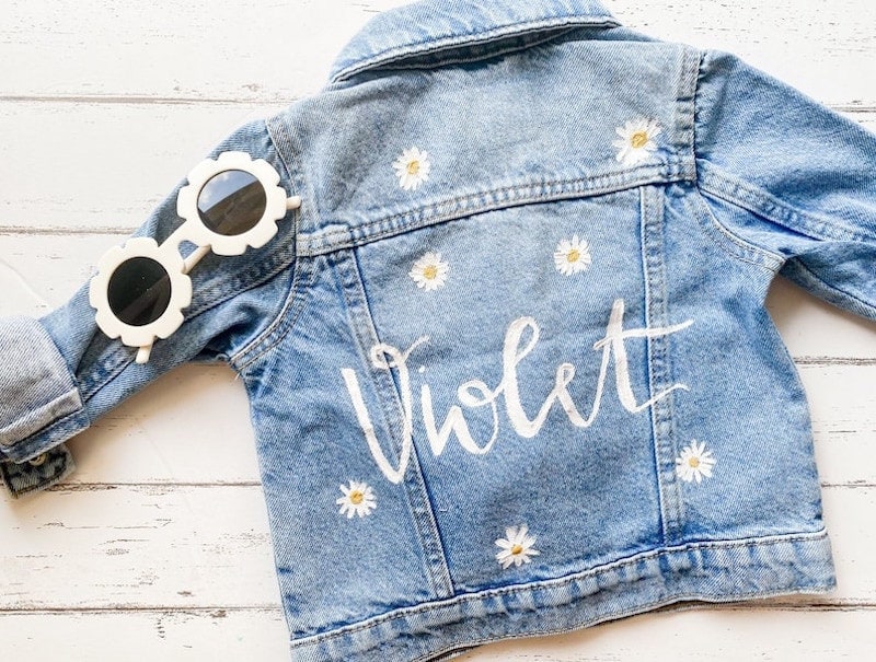 A custom denim kid's jacket personalized with their name and daisies.