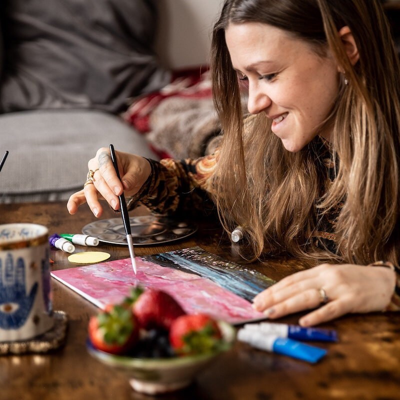 A candid shot of a woman working on a painting during a sip and paint party. A candid shot of a woman working on a painting during a sip and paint party.