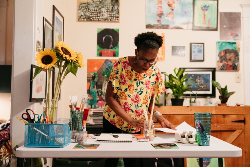 Mirlande works on a collage in her dining room studio.