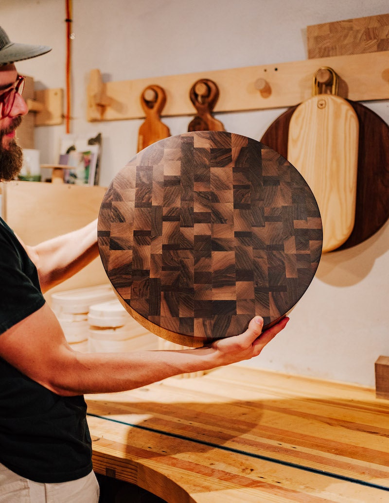 Cody holds up a handmade cutting board from his collection.