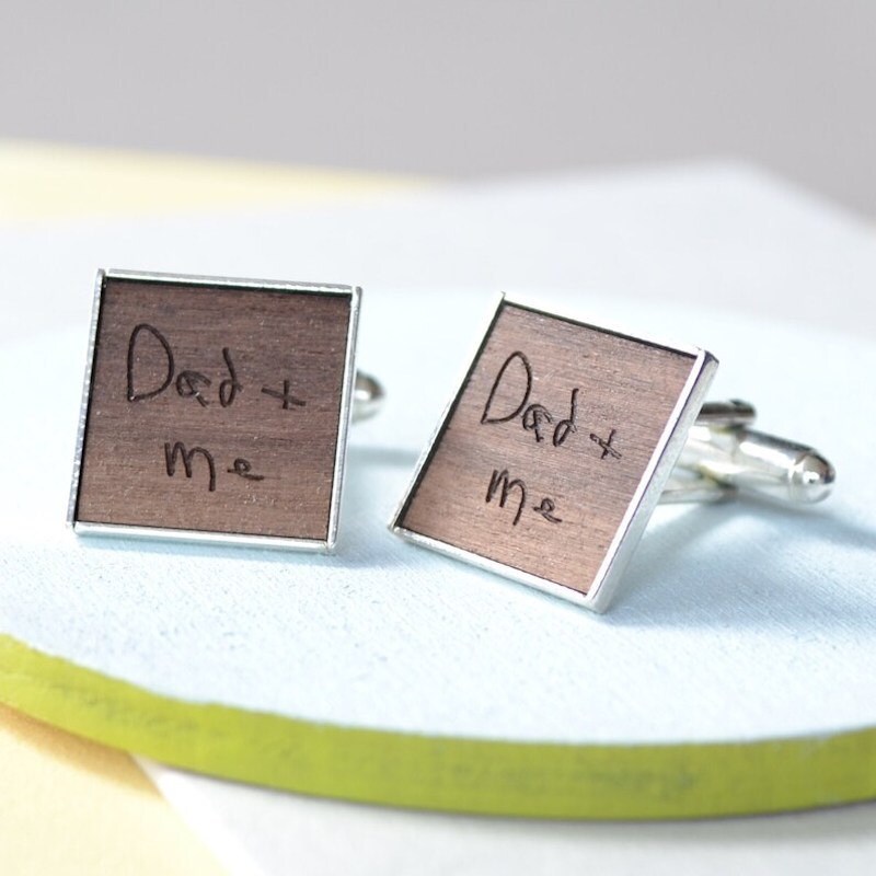 A set of personalized wooden cufflinks with someone's handwritten message on them.