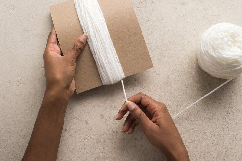 Hands winding yarn around the chipboard. Hands winding yarn around the chipboard.