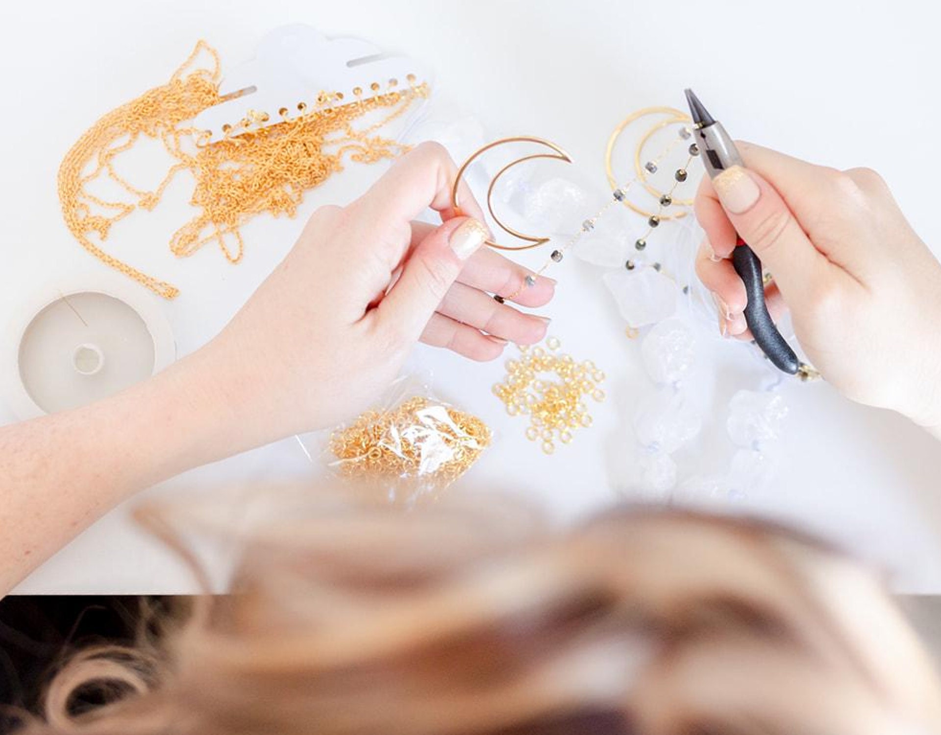 A person making jewelry using pliers and gold chain