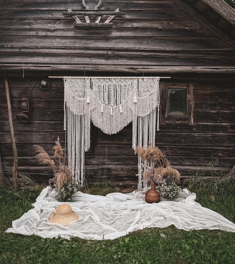 Macrame rustic wedding backdrop in front of weathered barn