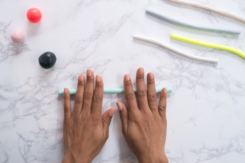 Hands rolling clay snake against a marble background. Hands rolling clay snake against a marble background.