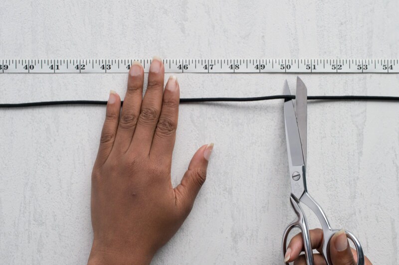 Image of hands cutting cord next to measuring tape. Image of hands cutting cord next to measuring tape.