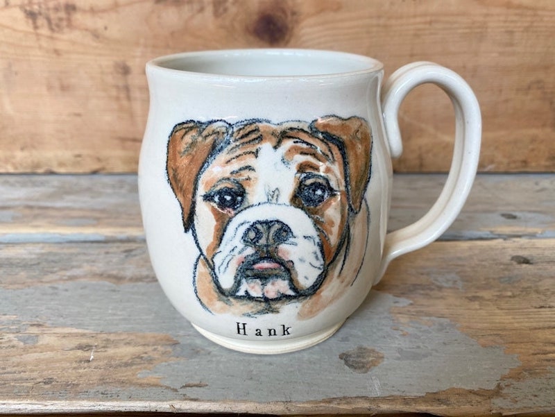 A personalized hand-painted mug with a dog's face on it.