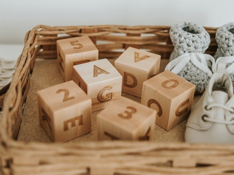 Wooden number and letter blocks in a basket with baby shoes