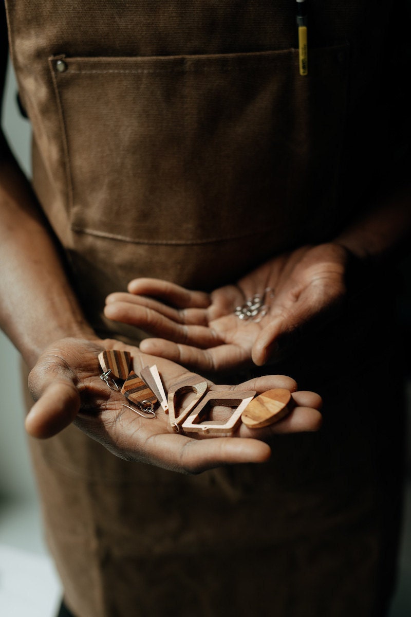 Open palms displaying an array of wooden earrings