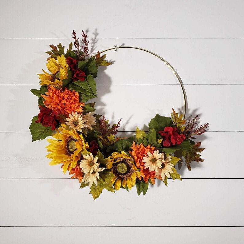 A fall-inspired hoop wreath with flowers against a white background.