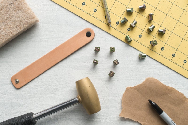 A flat-lay of materials needed to create stamped leather cuff bracelets.