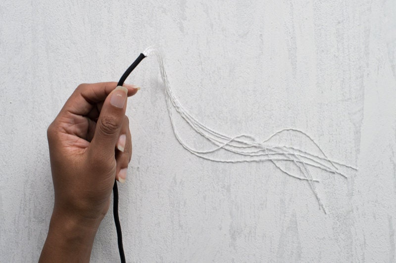 Image of a hand holding paracord with filler cords coming out of the end. Image of a hand holding paracord with filler coming out.