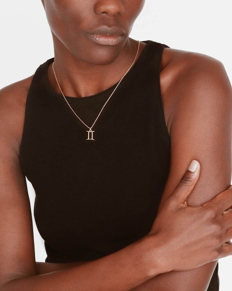 A Black woman wearing a gold Roman numerals necklace.