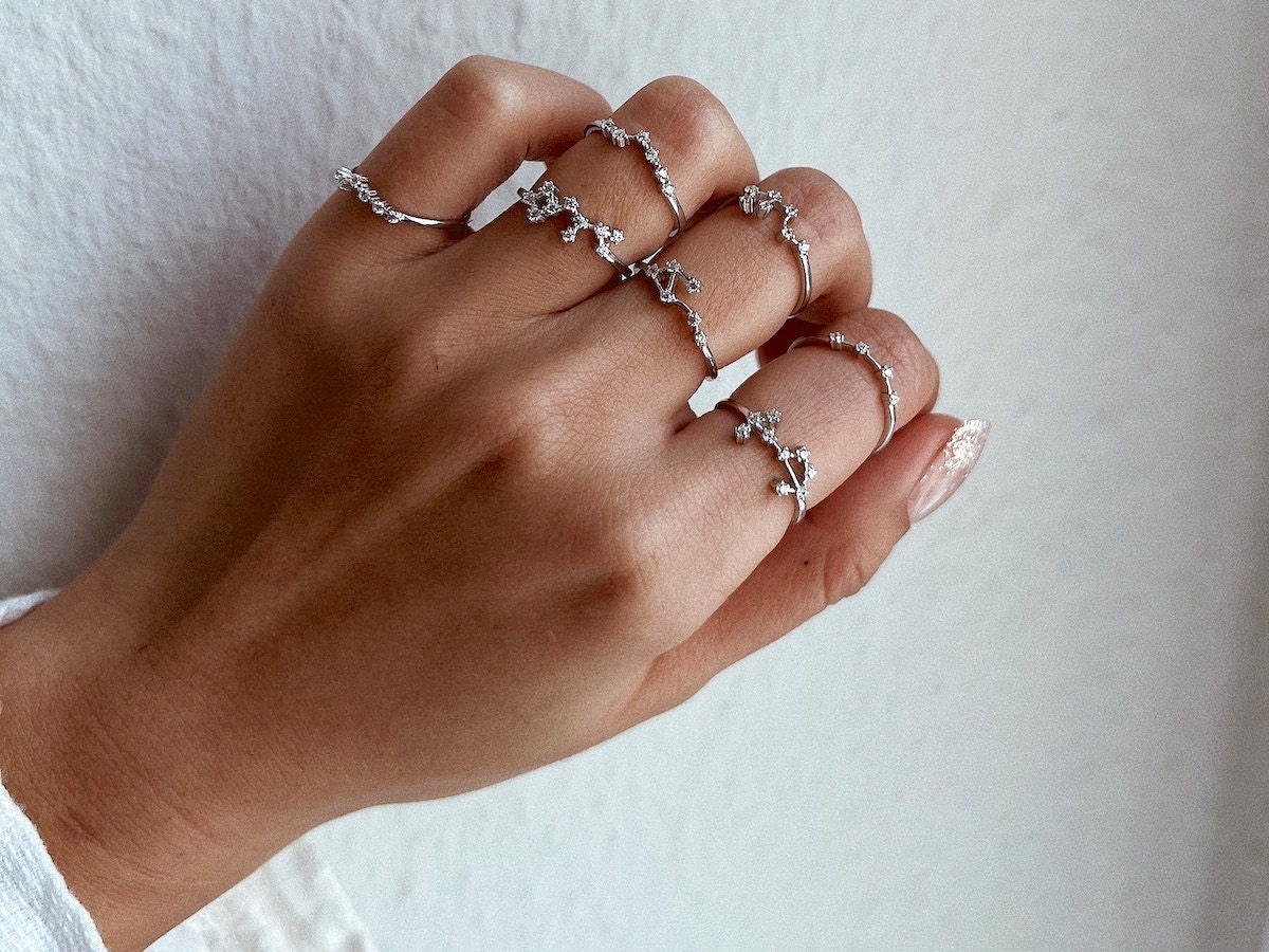 A hand modeling silver constellation rings — a unique birthday gift idea for her from Etsy.