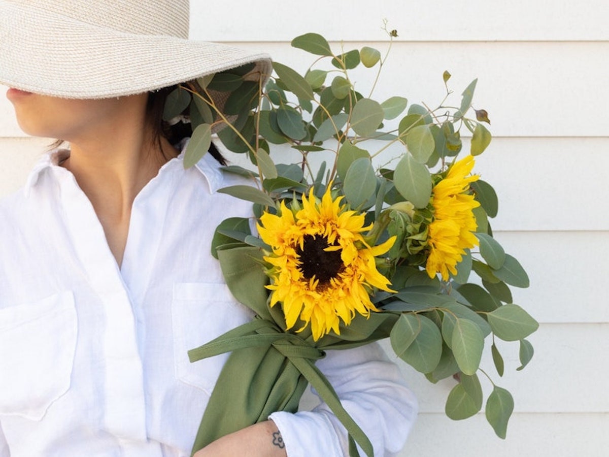 Woman in sun hat holding a bouquet of sunflowers