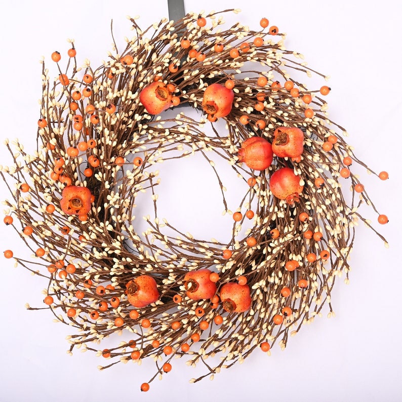 A fall wreath featuring pomegranate, berry, and twig fruit.