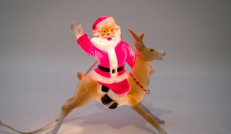 A vintage blow mold of Santa Claus riding on a reindeer.