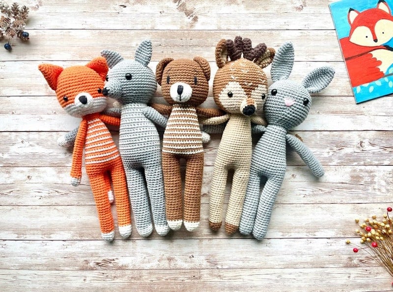 Five crocheted stuffed animals lay on a wooden surface