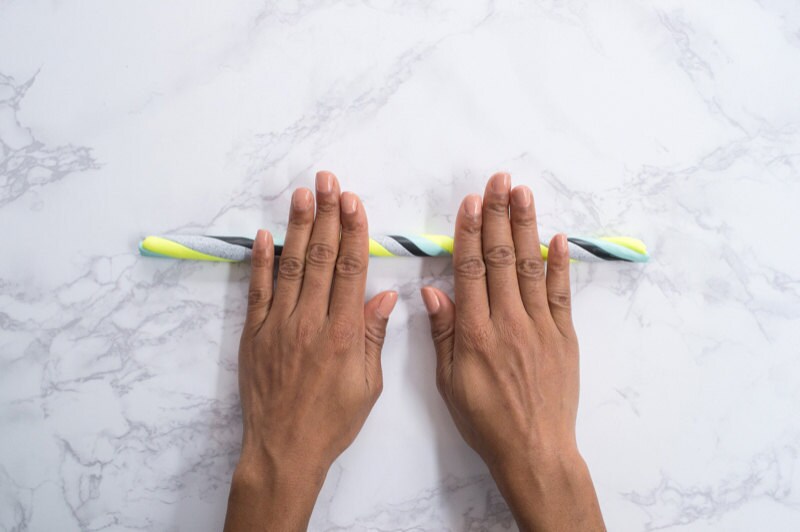 Hands rolling twisted clay snake against a marble background. Hands rolling twisted clay snake against a marble background.