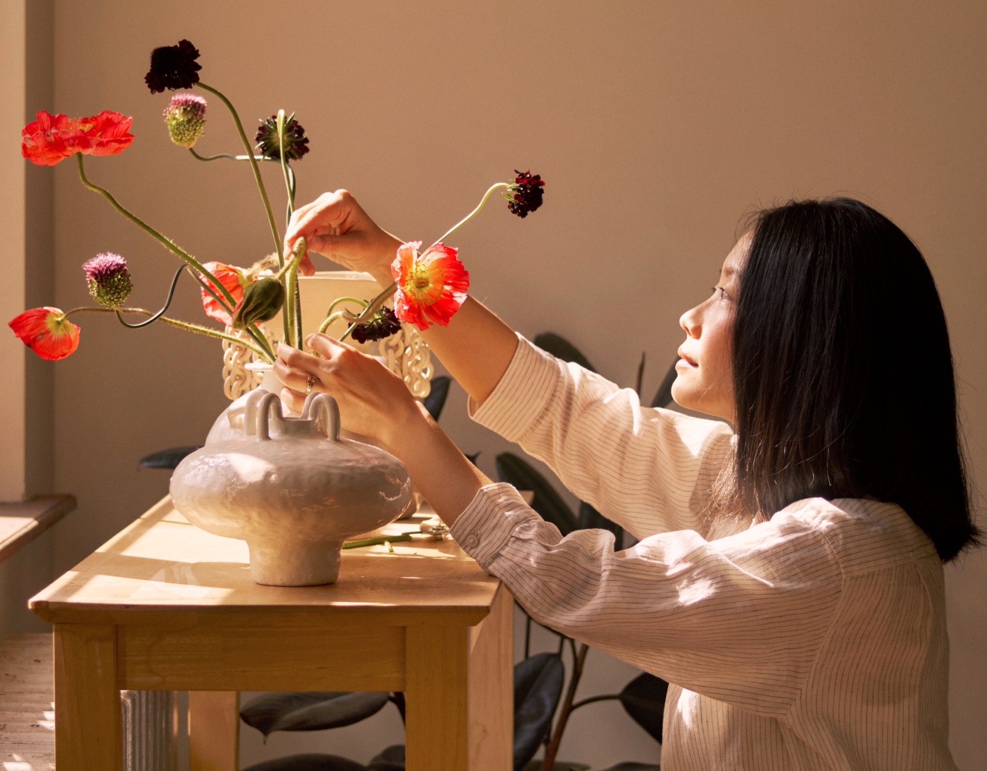 Mary adjusts delicate flowers in a ceramic vase