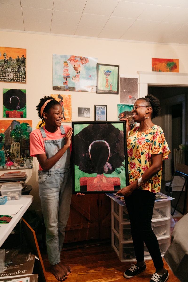 Mirlande and her daughter hold a framed print of