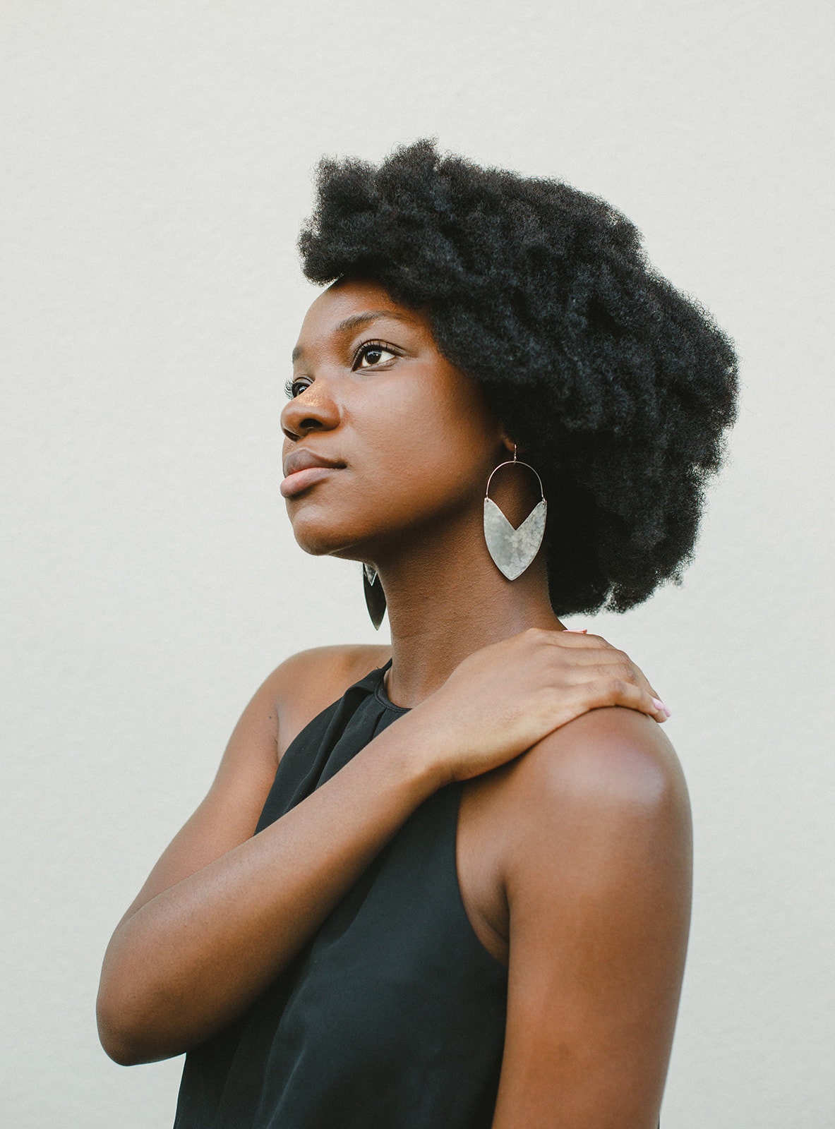 A Black woman wearing silver tulip shield earrings from Enarmoured.